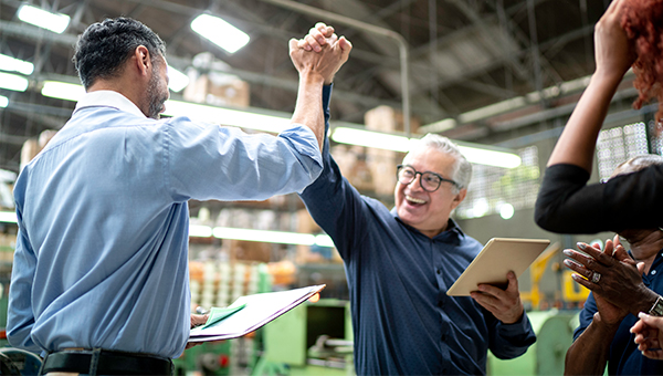 Coworkers holding documents high fiving in celebration