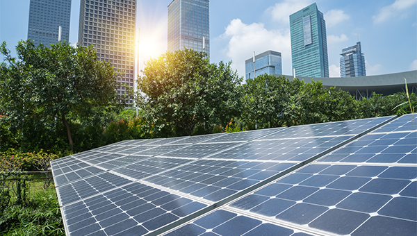 Solar panels on green land with metropolitan buildings in the background