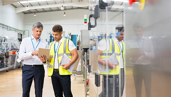 Factory workers reviewing data on a tablet computer