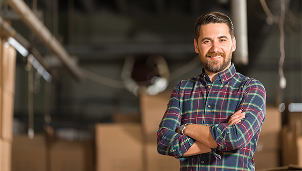 Man wearing a plaid shirt standing in a warehouse