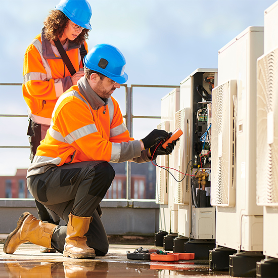 Two workers wearing PPE doing a test on  HVAC systems 