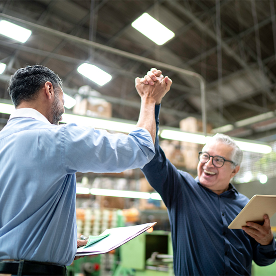 Coworkers holding documents high fiving in celebration