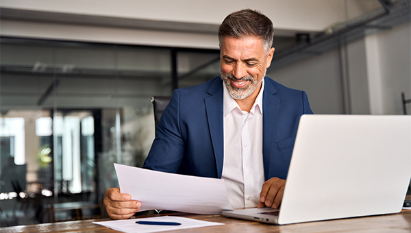 Businessman using laptop and reviewing documents