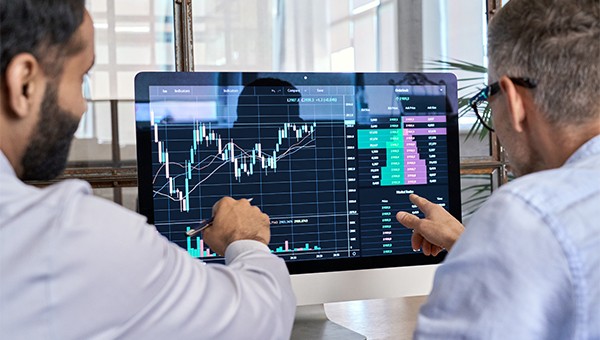 analysts pointing to charts on a computer