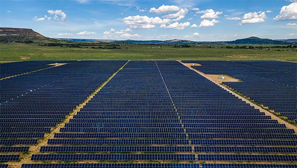 High angle shot of large solar farm with mountains and blue sky in the background