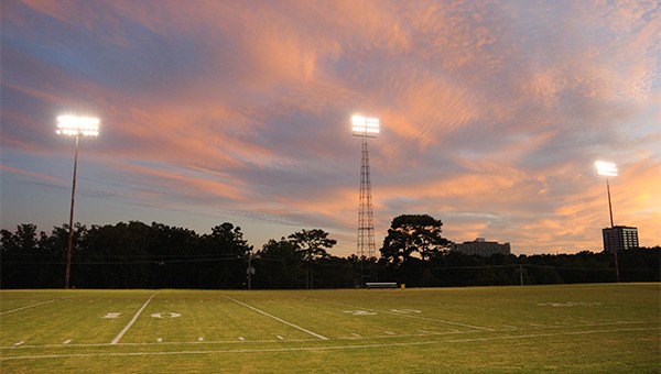 Football field at sunset with stadium lights on