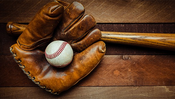 Close up of a baseball in a baseball mitt and bat