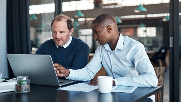 co-workers sitting at a table working on a laptop